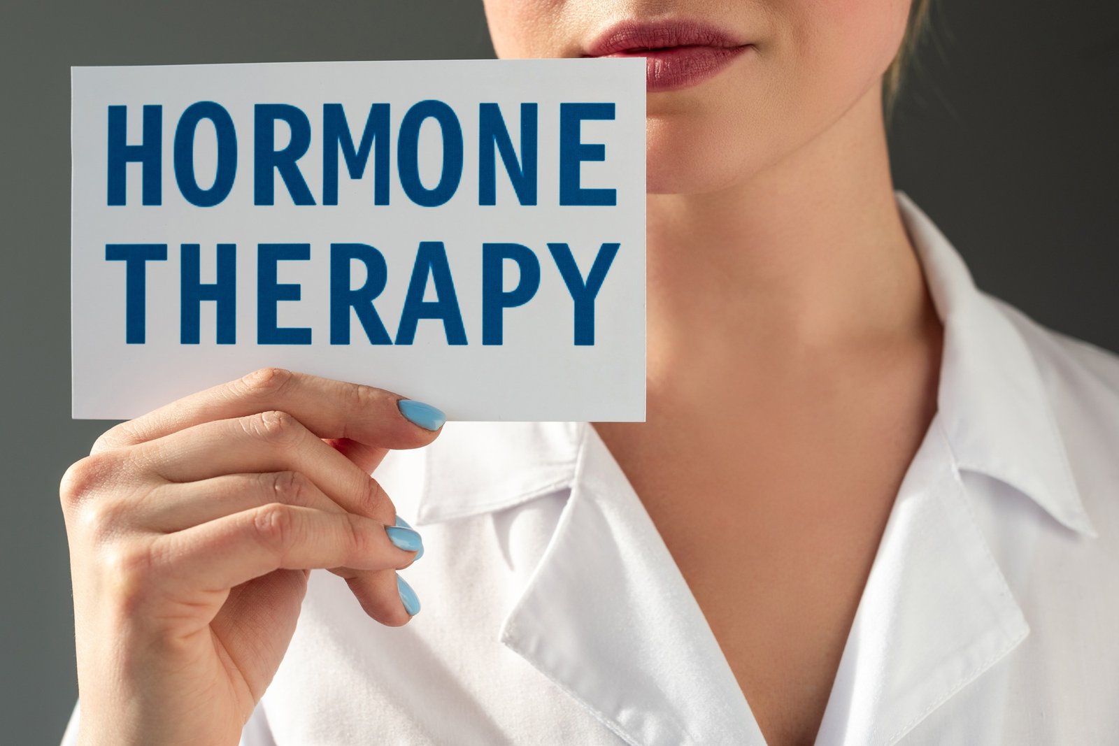 Cropped view of doctor holding card with hormone therapy lettering isolated on grey